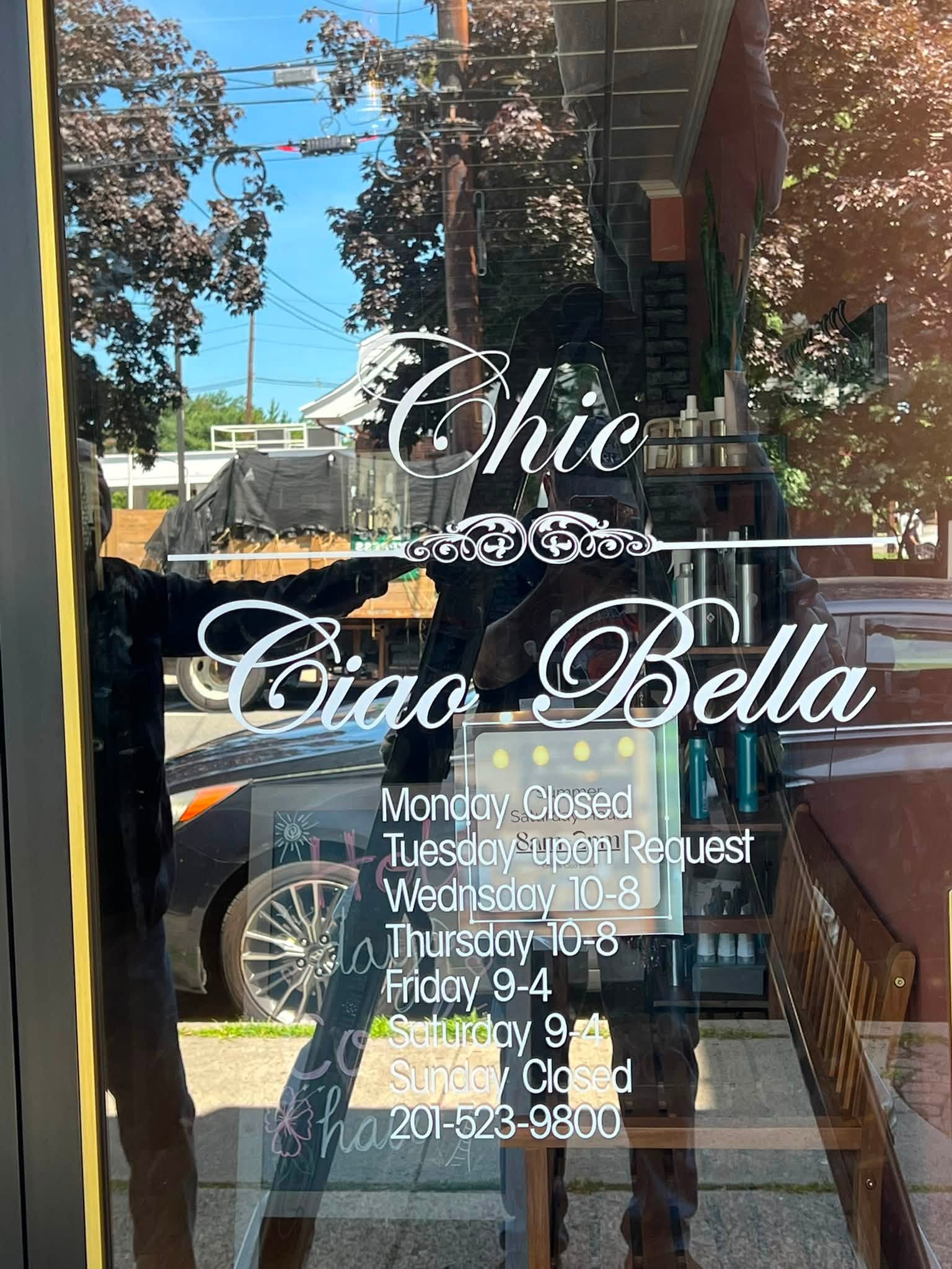 Script vinyl lettering and hours on a salon glass door